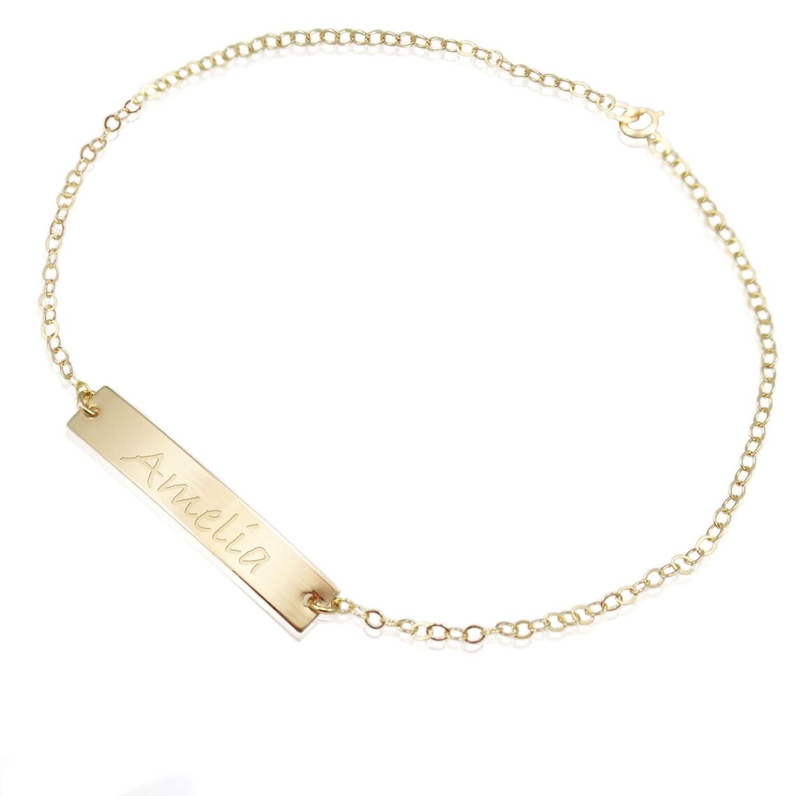 Gold bracelet with a bar pendant engraved with 'Amelia' on a white background