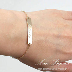 Rose gold bracelet with a nameplate on a wrist, branded 'Ann Bijoux'.