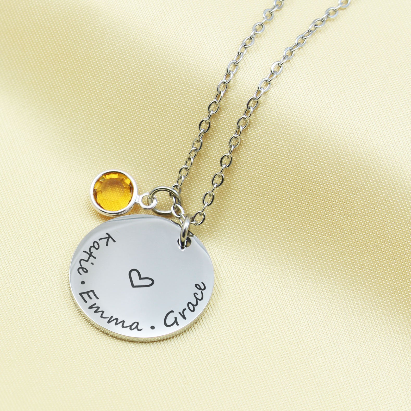 Perfectly balanced between elegance and sentiment, this piece features a polished silver-finish disc engraved with three names of your choice, encircling a delicate hand-drawn heart.