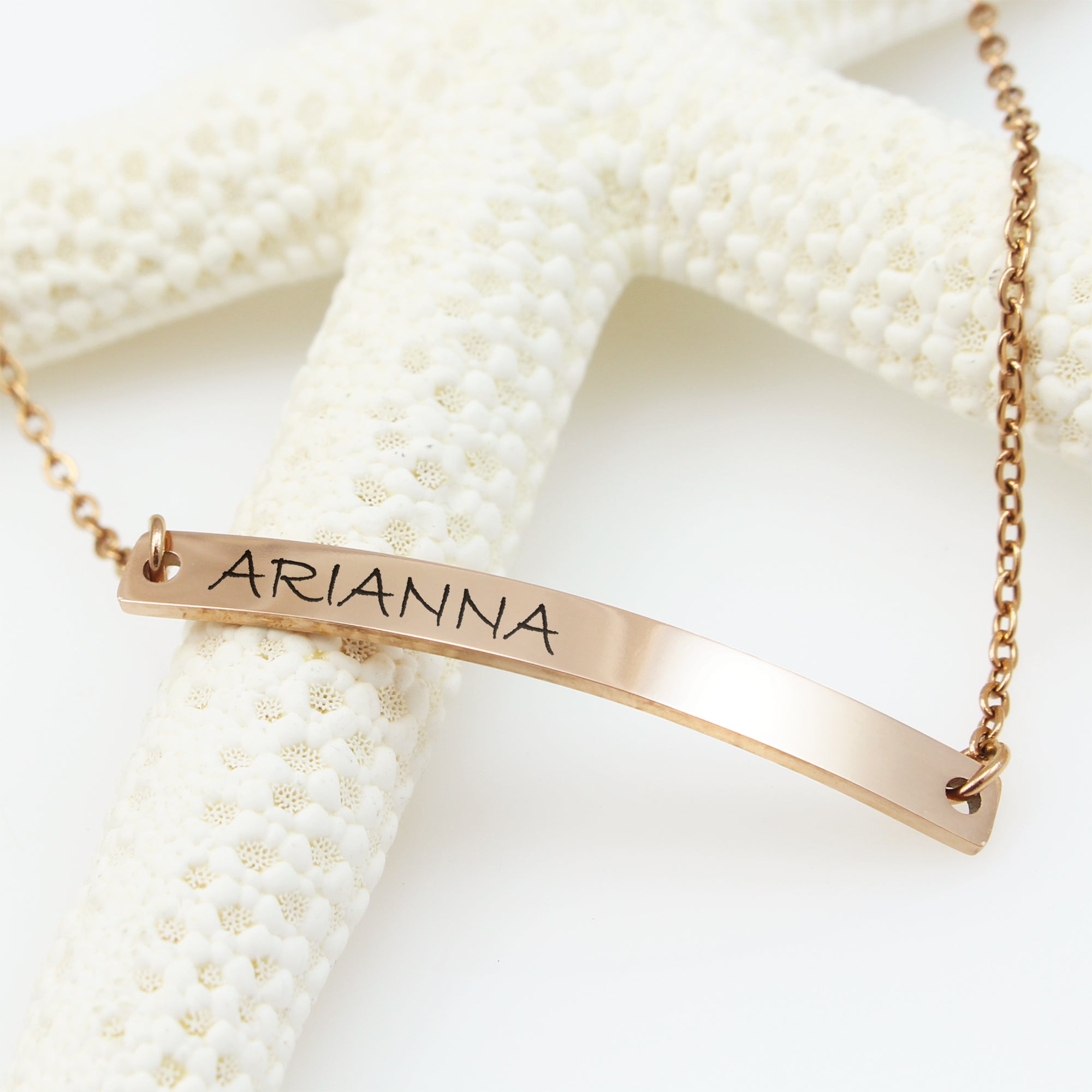 Gold bar necklace with 'ARIANNA' engraving on a white background