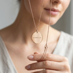 Rose gold necklace with a round pendant on a blurred background