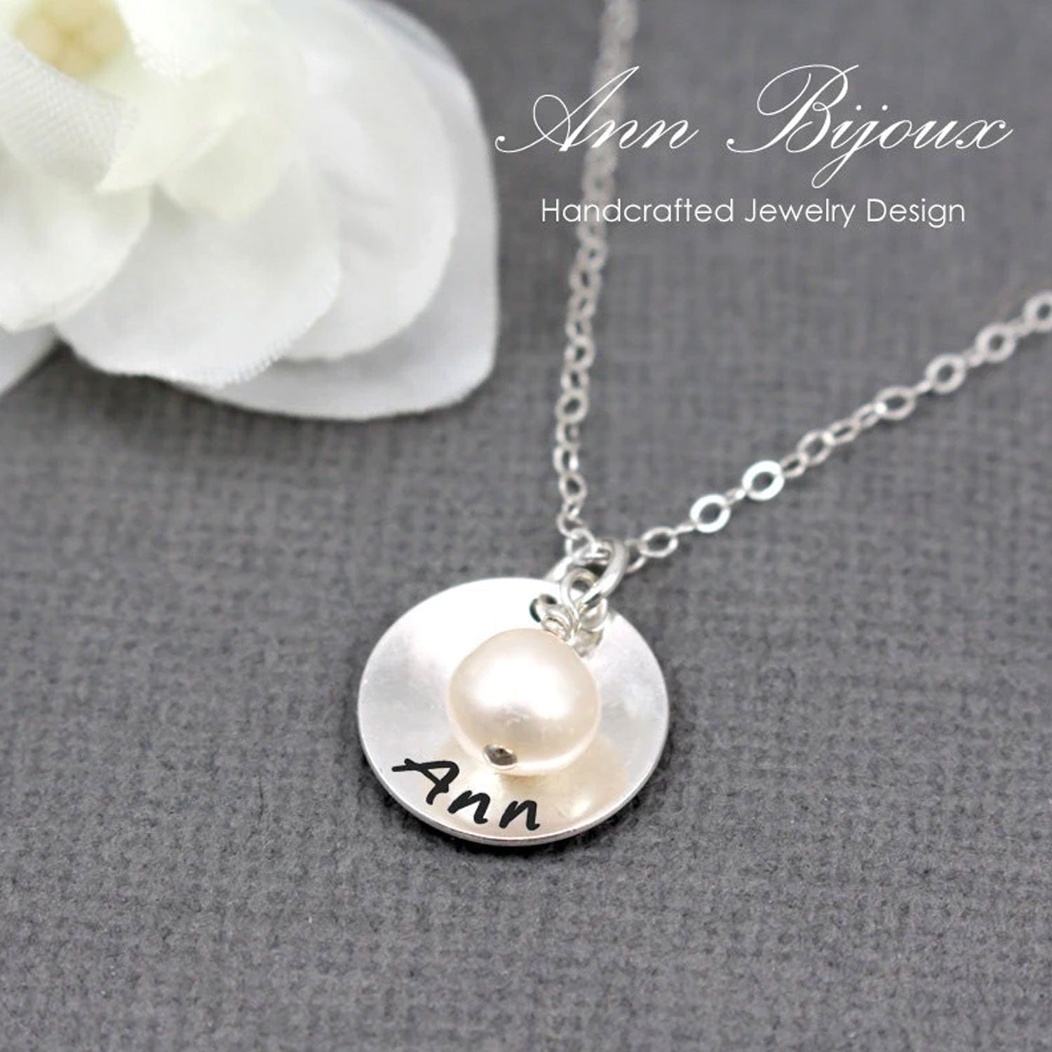 Silver necklace with a round pendant featuring the name 'Ann' on a gray background.
