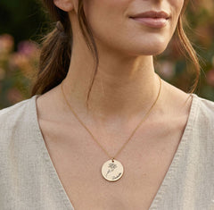 Woman wearing a gold necklace with a circular pendant outdoors