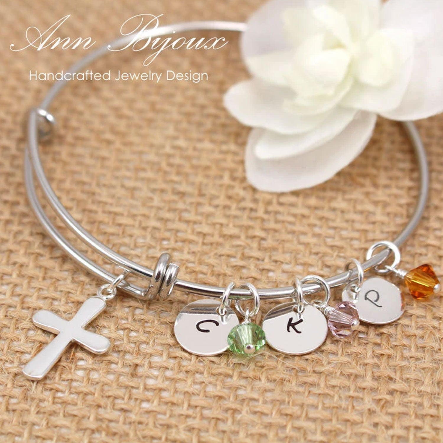Silver bracelet with charms and beads on a textured surface with 'Ann Bijoux' branding.