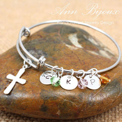 Silver bracelet with charms on a stone surface, featuring the brand 'Ann Bijoux'.