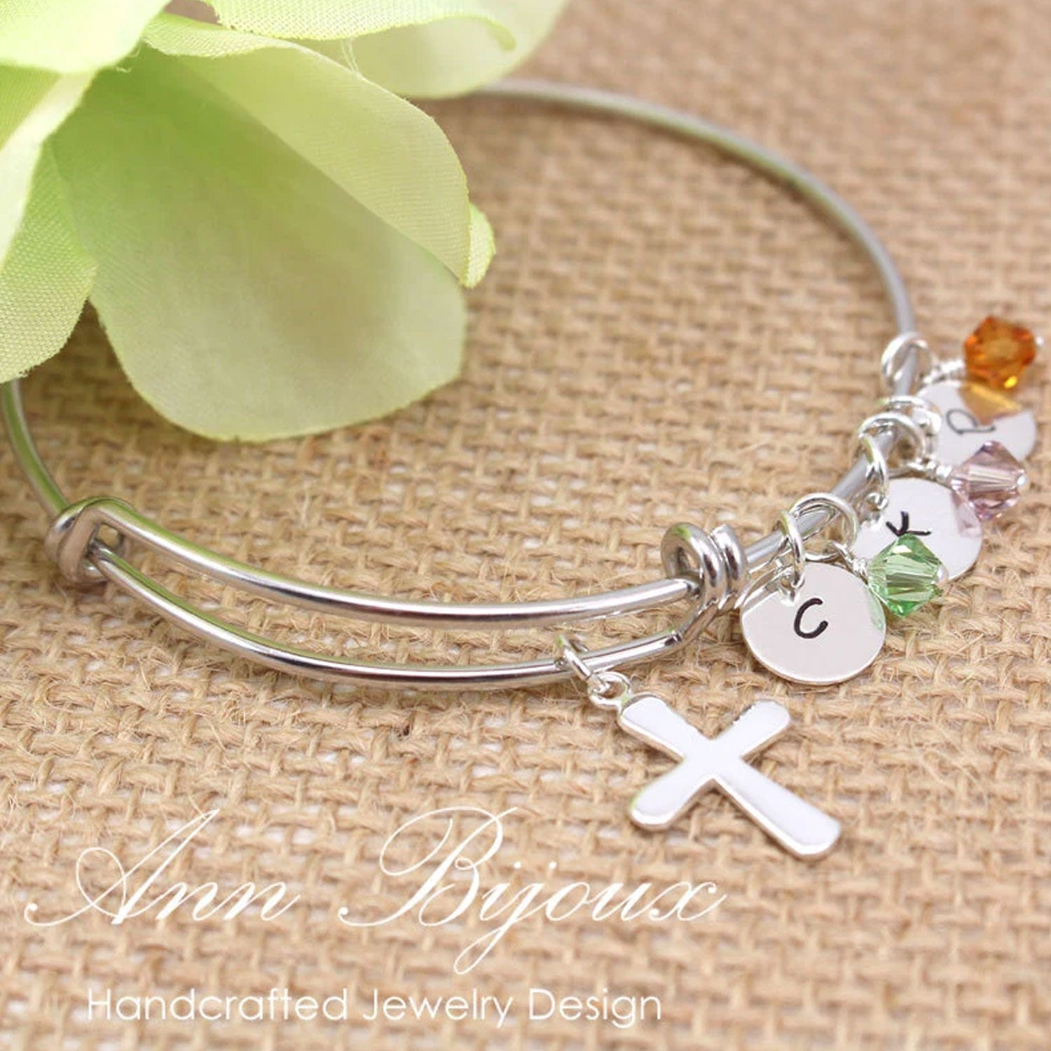 Silver bracelet with charms on a textured surface with flowers