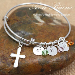 Silver bracelet with charms on a stone surface, featuring 'Ann Bijoux' branding.