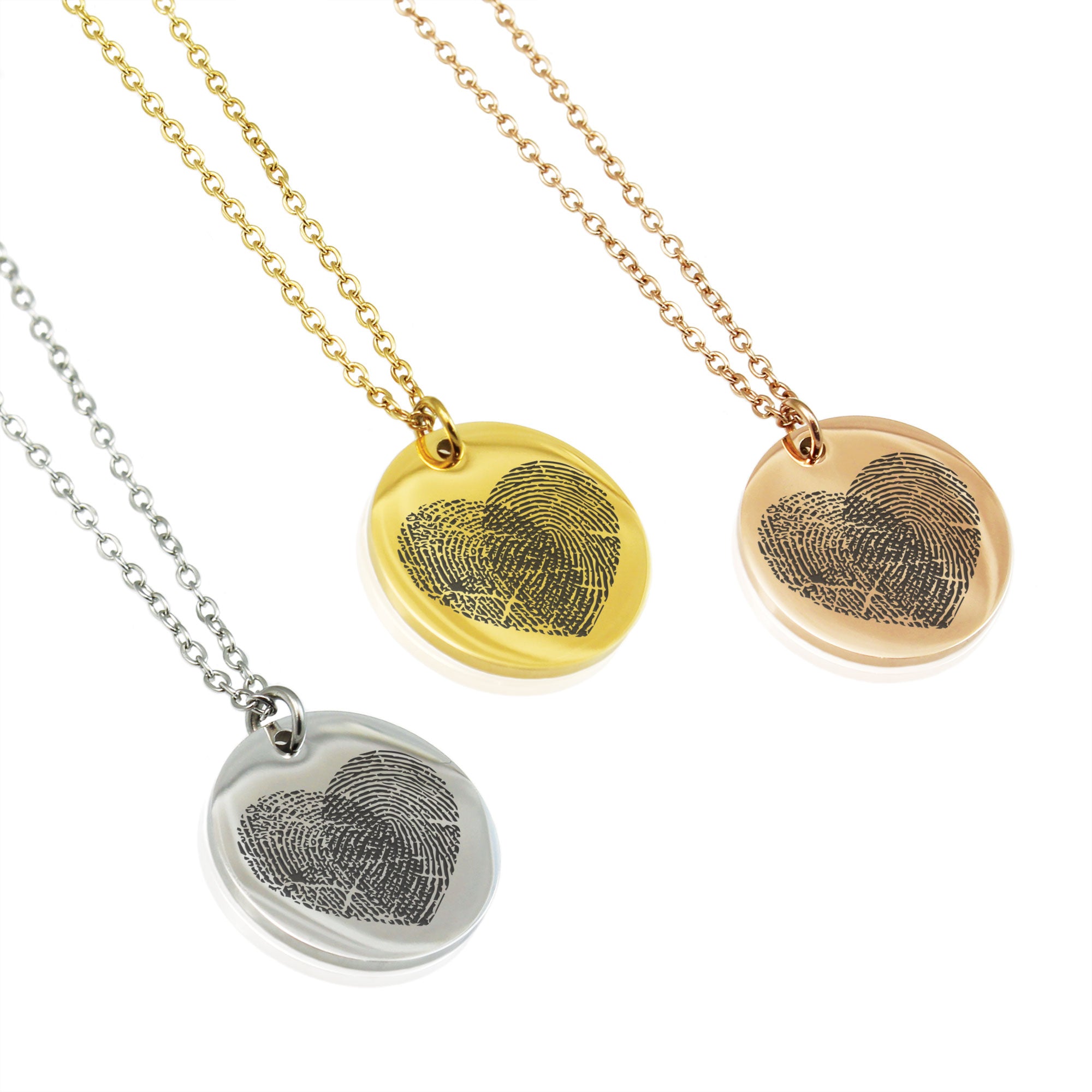 Three heart-shaped fingerprint pendants on gold, silver, and rose gold chains.