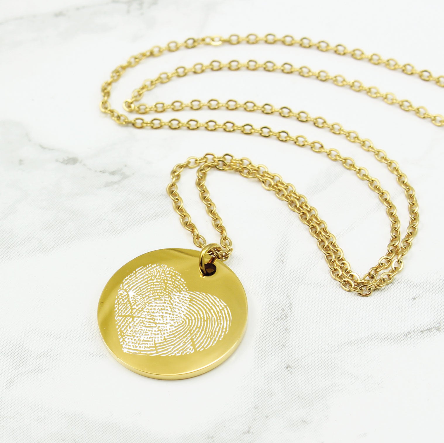 Gold fingerprint necklace on a marble background