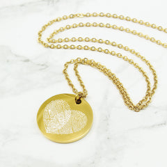 Gold fingerprint necklace on a marble background