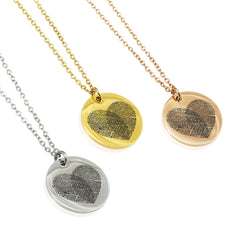 Three heart-shaped fingerprint pendants on gold, silver, and rose gold chains.