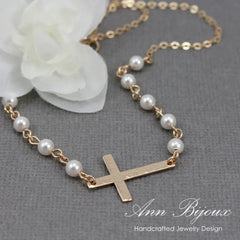 Handcrafted gold hammered cross necklace featuring a small white pearl accent on a delicate gold link chain. A unique religious jewelry piece perfect for baptism, confirmation, or everyday faith-based style.