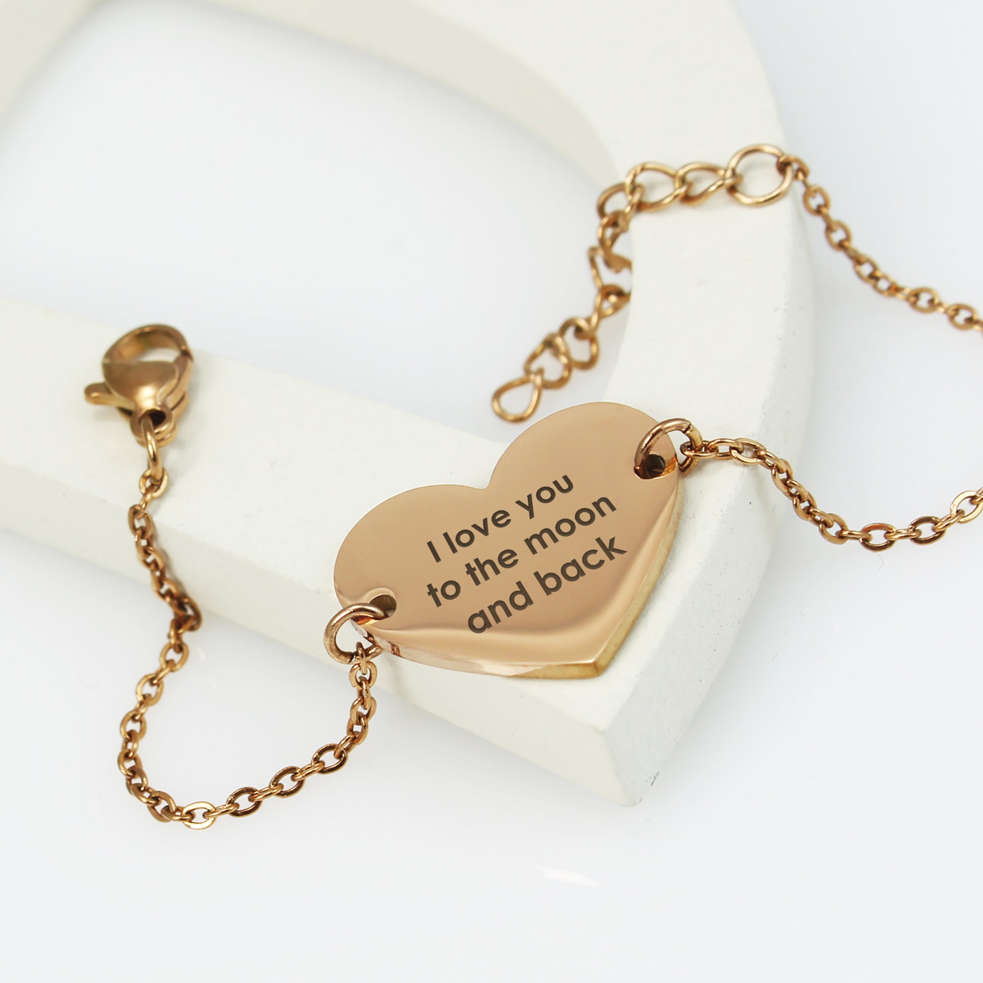Rose gold heart-shaped pendant with 'I love you to the moon and back' engraving on a white background