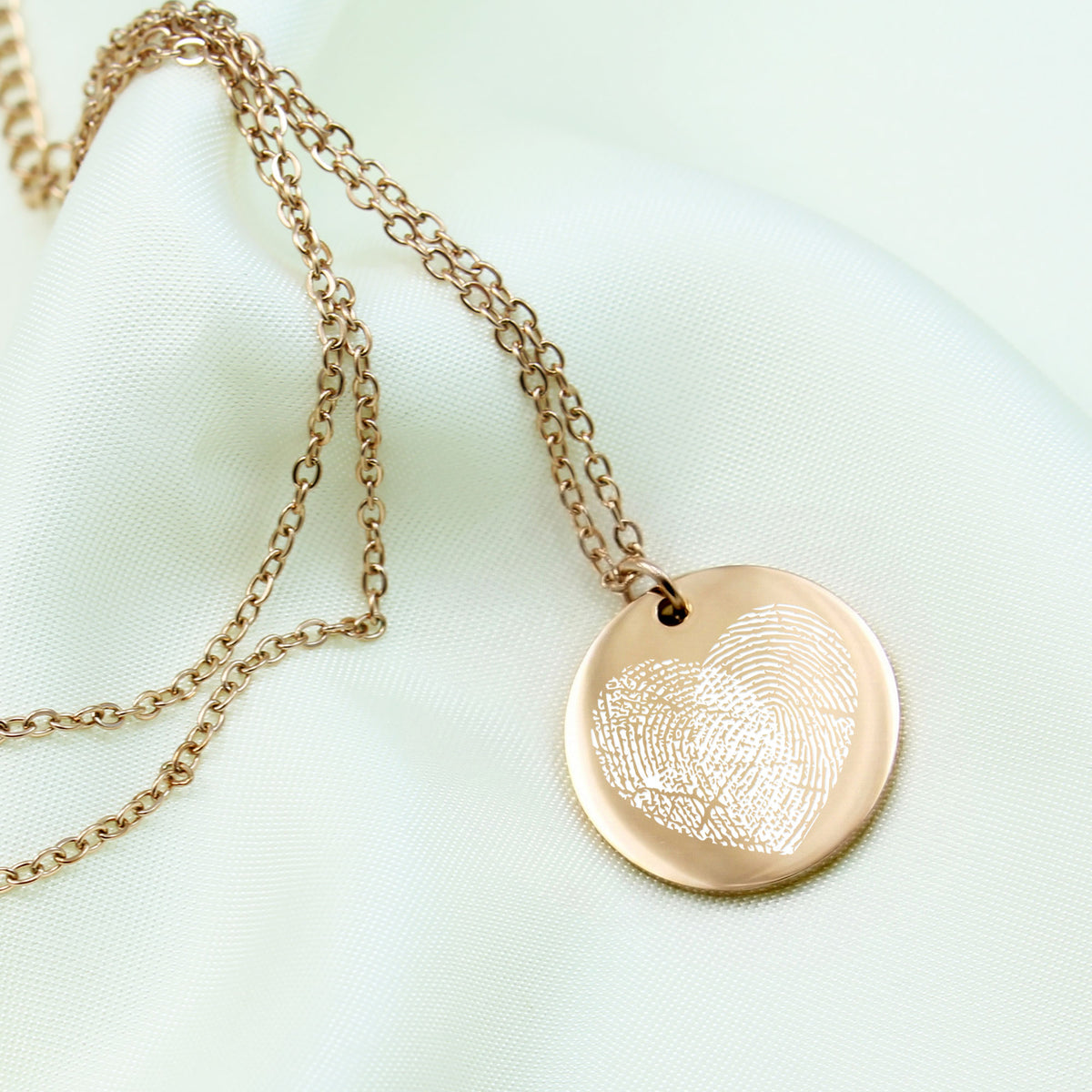 Rose gold fingerprint necklace on a light green background